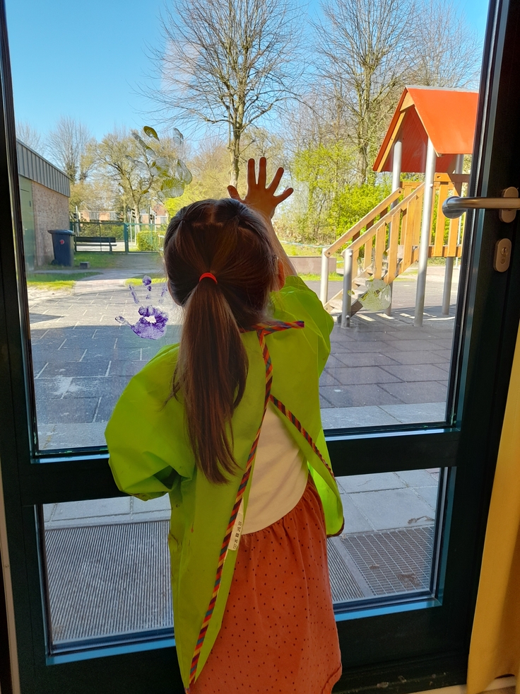 Foto Kindergartenkind macht Abdrücke mit Hand an der Scheibe