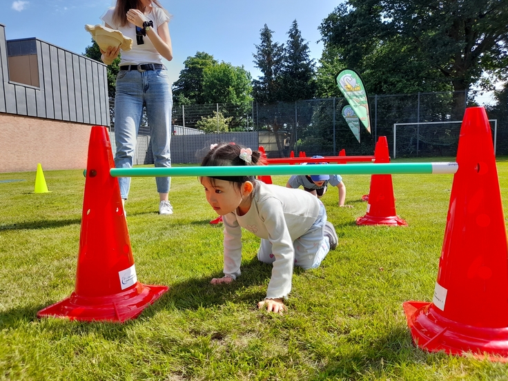 Foto eines Kindergartenkindes, das unter einem Hindernis hindurch krabbelt