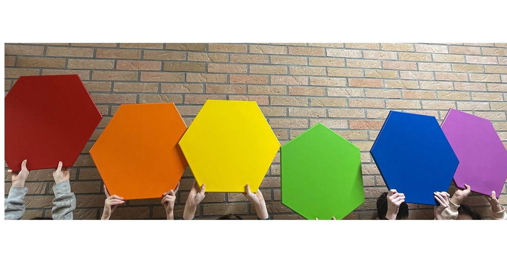 Foto Kinderhände halten sechs Kacheln in den Farben rot, orange, gelb, grün, blau und lila